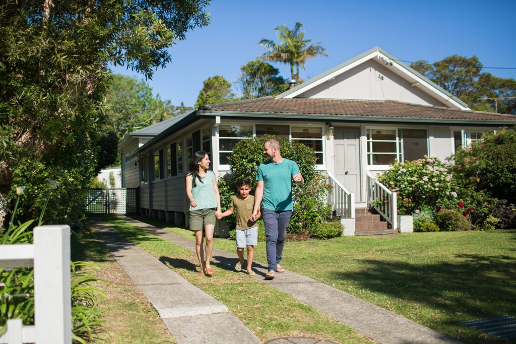 Boy holding hands of parents while walking in lawn
